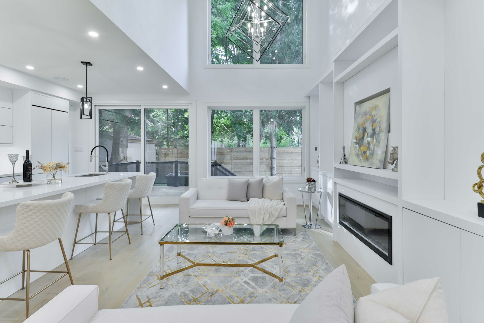 A bright, double-height luxury living room with gold accents, a fireplace, and full-height windows