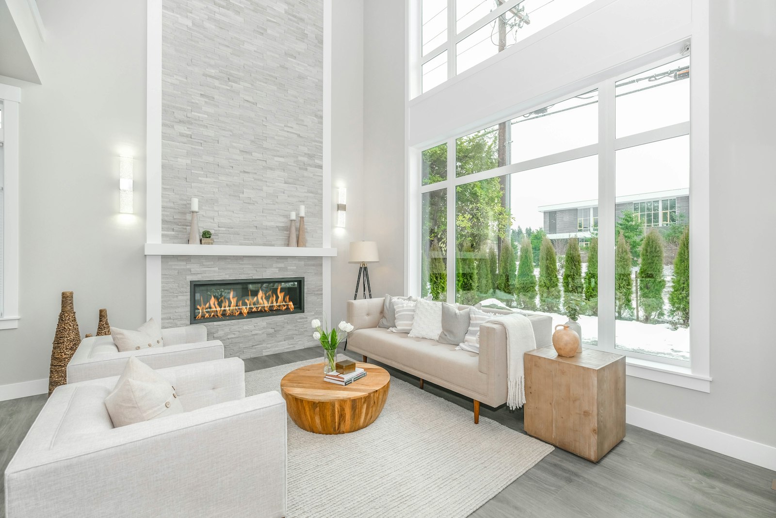 A white sofa beside a large glass window in a bright, minimal interior