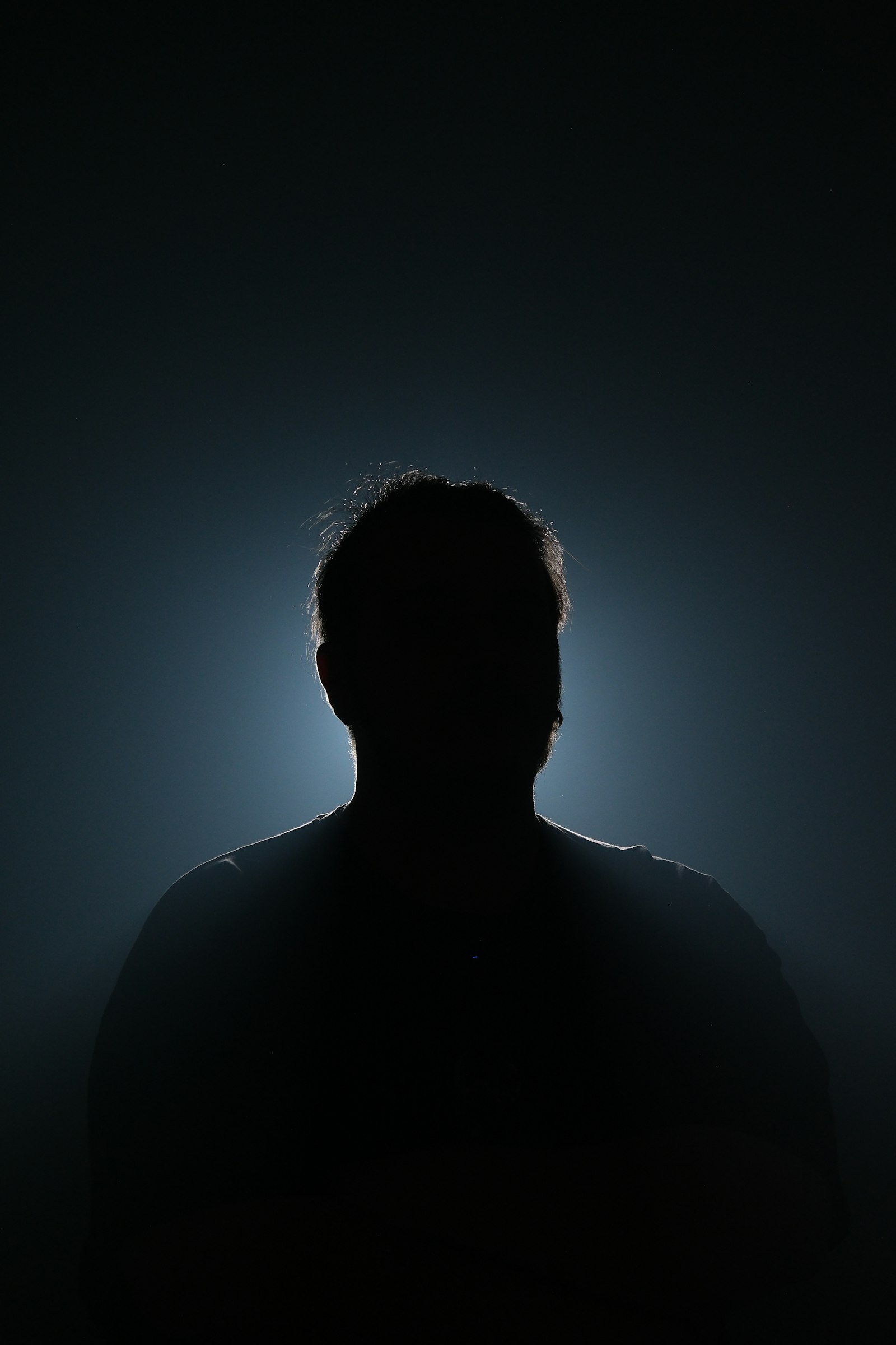 A silhouetted figure standing in dramatic shadow and backlight