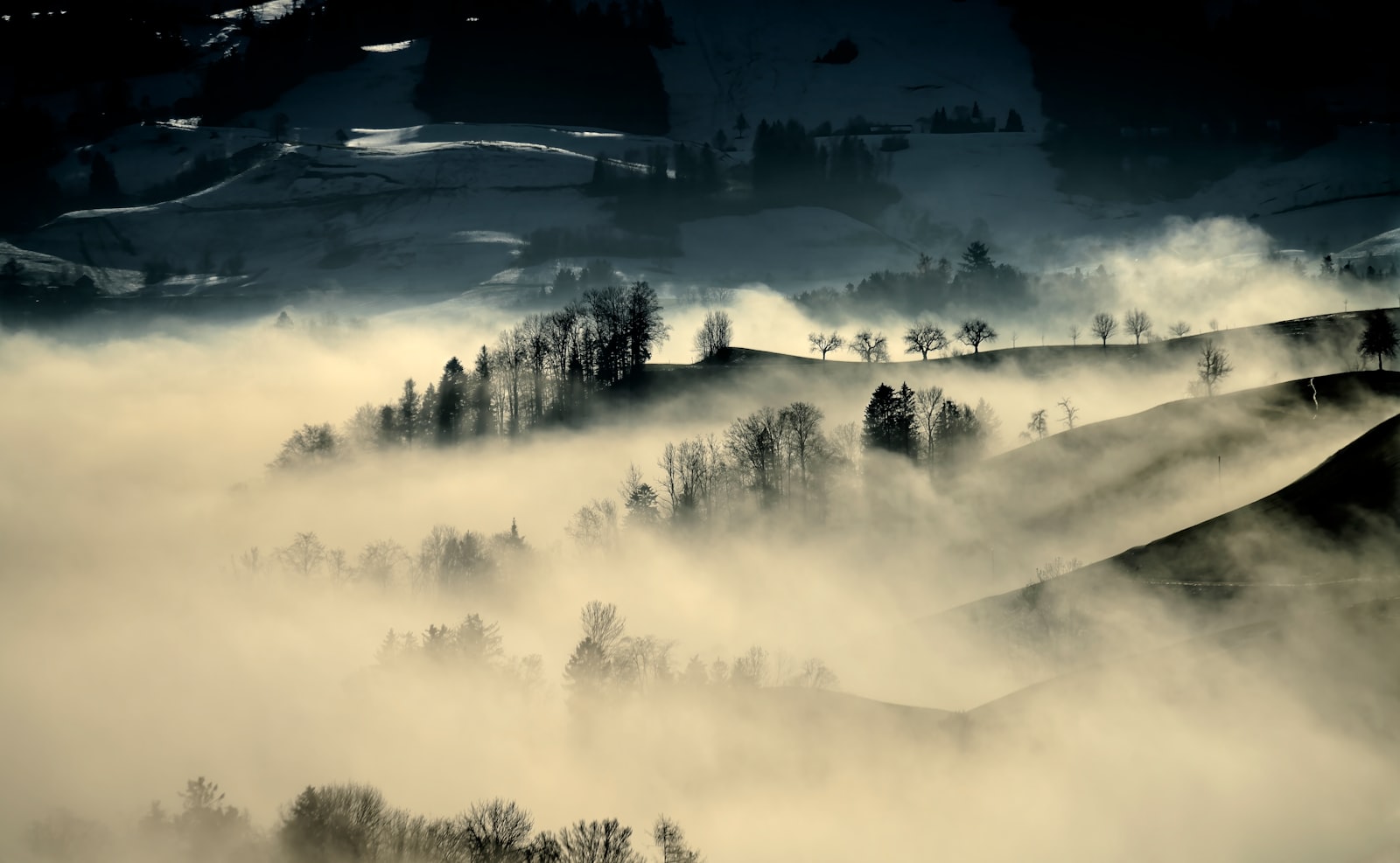A black and white photograph of a mountain peak partially covered in fog